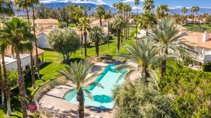 Ein Resort mit großem Pool, Palmen und einem Bergpanorama.