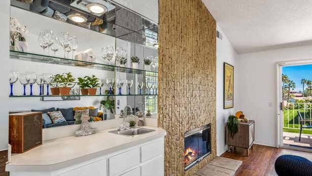 Ein modernes Wohnzimmer mit Kamin, einem Glastischchen mit Dekoration und Blick ins Freie.