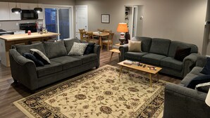 Ein modernes Wohnzimmer mit zwei Sofas, einem Couchtisch und einem gemusterten Teppich.