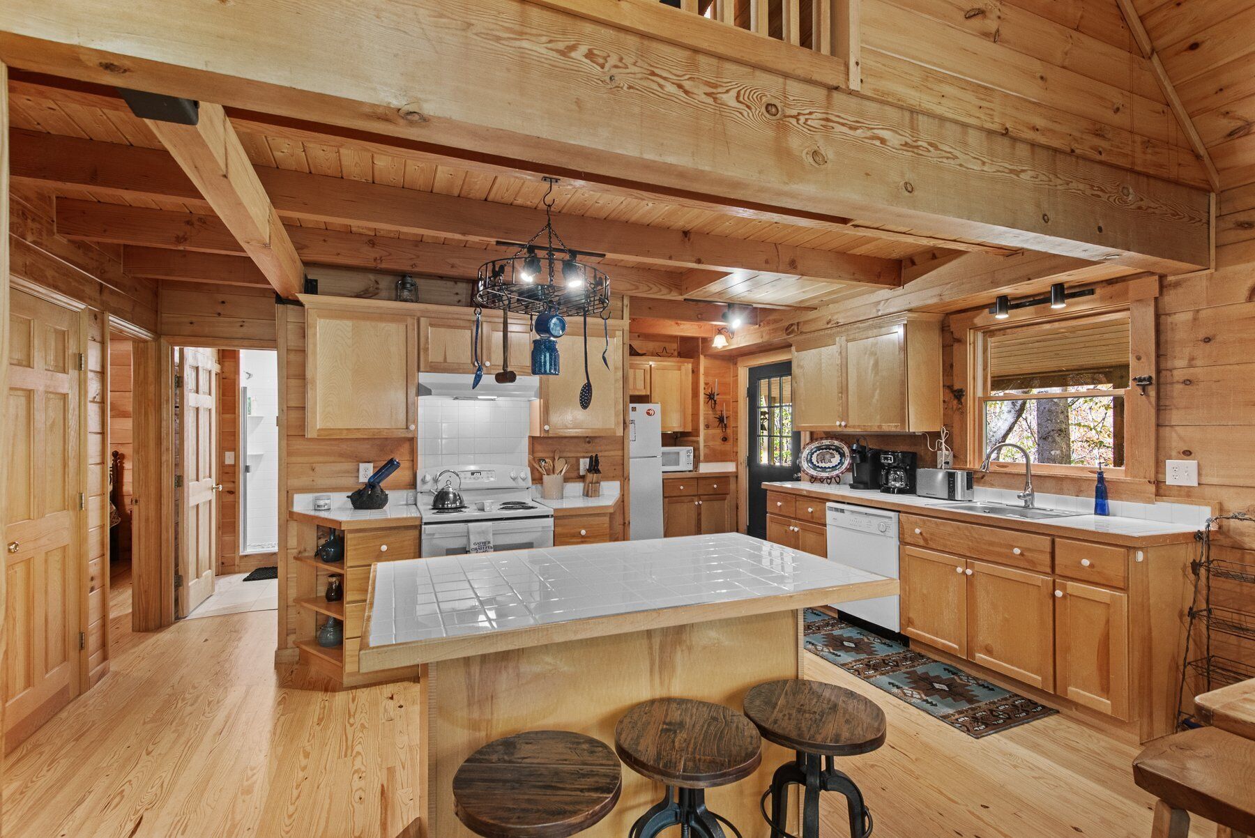 Una cocina tipo cabaña de madera con una isla central, armarios de madera y un ventanal grande.