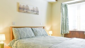 A neatly made bed with patterned bedding, a bedside lamp, and a painting on the wall. - 2 bedroom accommodation in Lovington, near Somerton (Lovington, near Somerton)