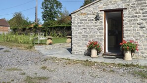 A stone building with a wooden door, a small garden with potted plants, and a clear sky. - 2 bedroom accommodation in Lovington, near Somerton (Lovington, near Somerton)