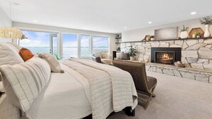 Ein Schlafzimmer mit einem großen Bett, einem Kamin und Meerblick.