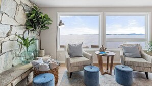 Ein gemütlicher Raum mit Steinwand, zwei Sesseln, einem kleinen Tisch und Blick aufs Meer.
