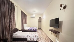 A room with two beds, a TV, and a small table. - Bait Alaqaba Resort and Dive Center (Aqaba)