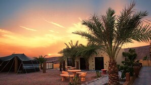 A desert-style outdoor area with a tent, palm trees, and a building with a door and windows. - Bait Alaqaba Resort and Dive Center (Aqaba)