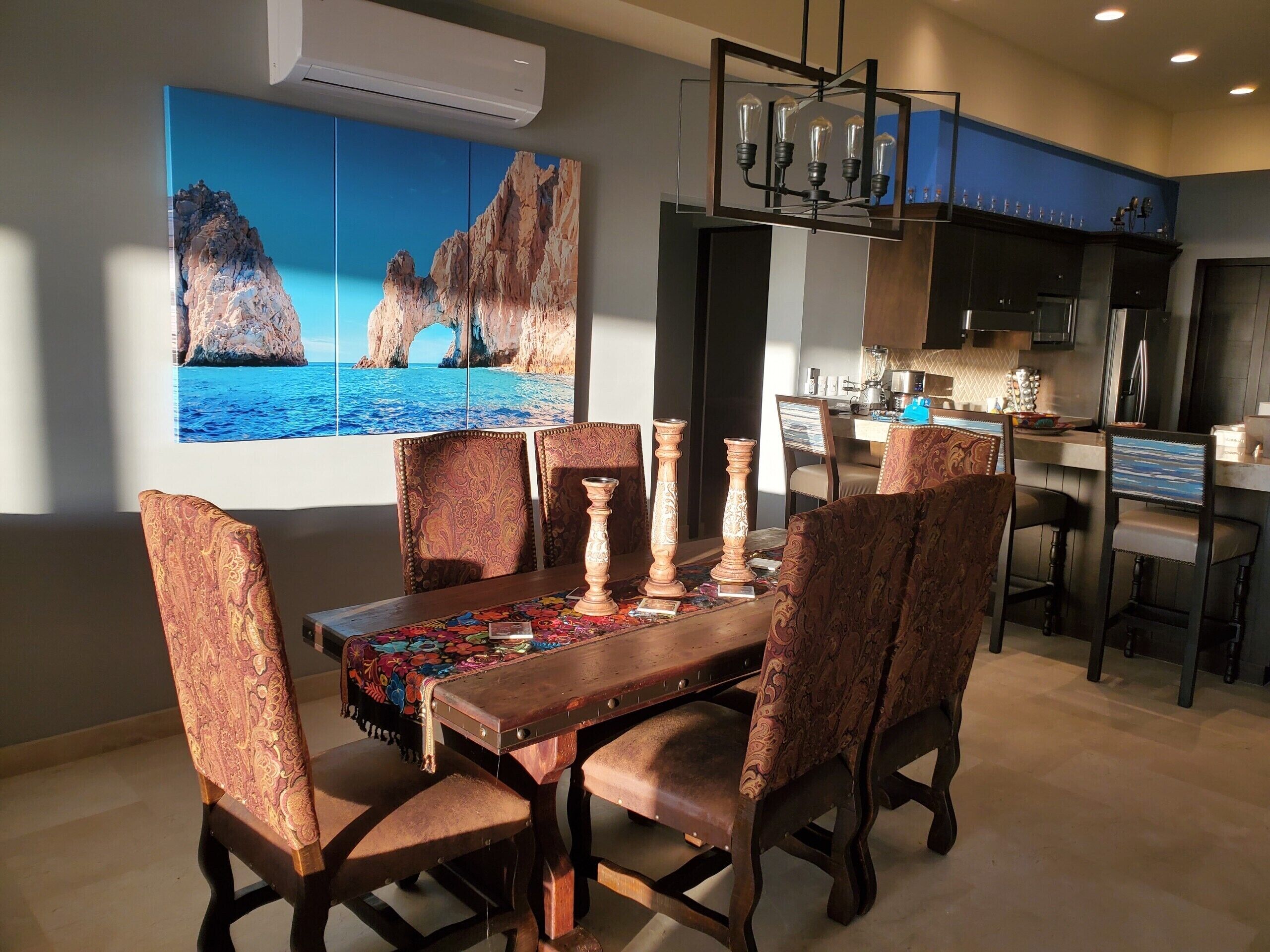 A dining area with a wooden table, patterned chairs, and a colorful table runner.