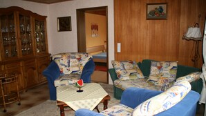 Una sala de estar con un sofá azul, un aparador de madera y una mesa con sandía.