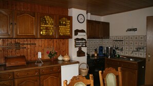 Una cocina con armarios de madera, un refrigerador, un lavamanos y una zona de comedor con sillas.