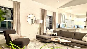 A modern living room with a sofa, armchairs, a coffee table, and a floor lamp. - Bayshore Beach House - Walk to Nokomis Beach!  Close to Siesta Key, Venice Beach (Nokomis)