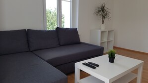 Ein modernes Wohnzimmer mit einem grauen Ecksofa, einem weißen Couchtisch und zwei Fernbedienungen.
