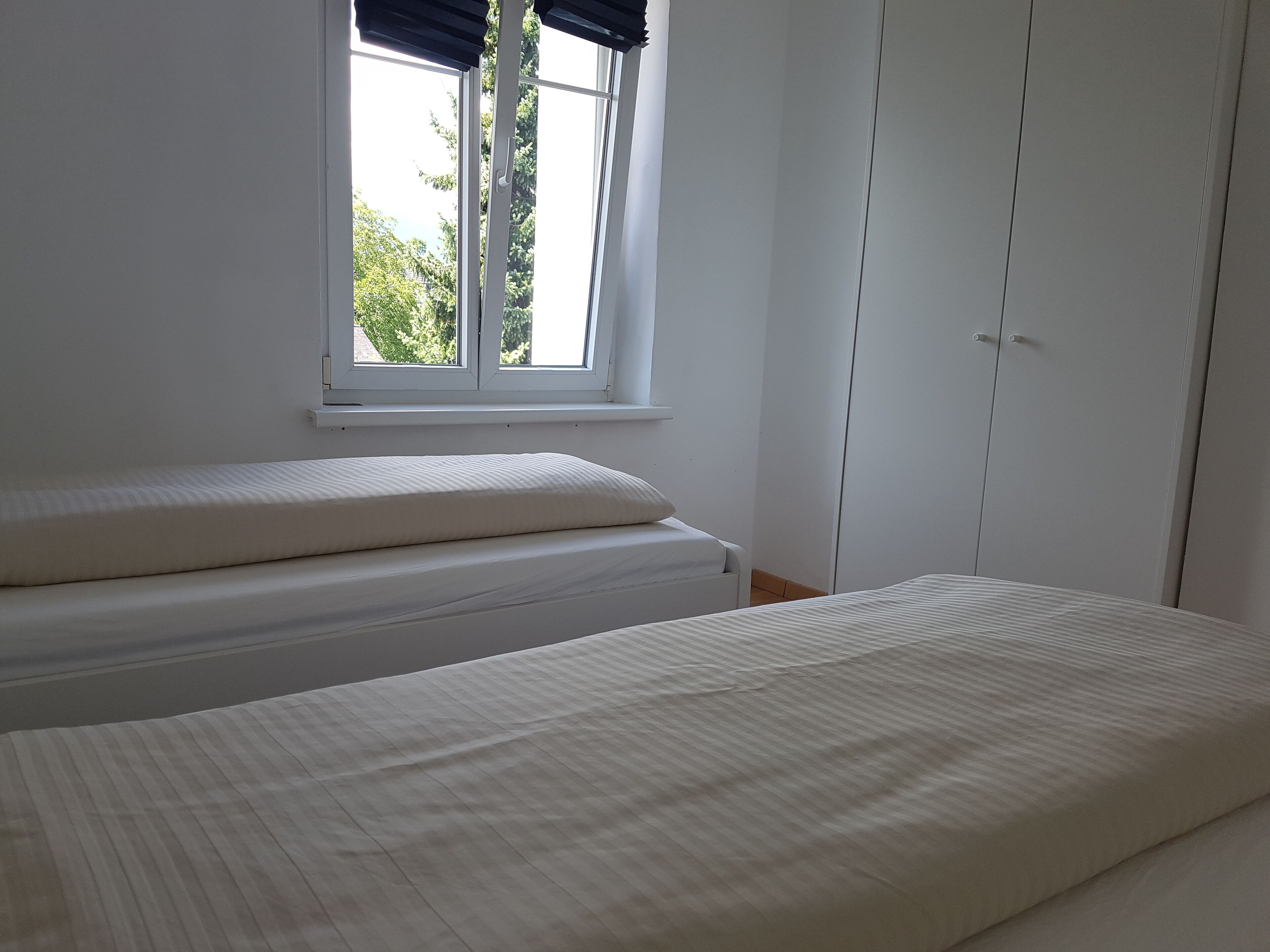 Ein Schlafzimmer mit Bett, Fenster und Kleiderschrank.