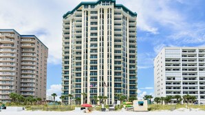 A high-rise hotel with multiple balconies, located near a beach with palm trees and a sandy shore. - Great beachfront condo!  Best View in Destin! Jade East Towers unit 920! (Destin)