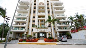 A multi-story hotel with a central entrance, balconies on each floor, and a symmetrical facade. - Resorto Condominio frente al mar directamente en el océano - Vista marina (Marina Mazatlán)