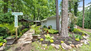 A cottage with a garden path leading to the entrance, surrounded by lush greenery and trees. - Eureka Uptown Garden Cottage (Eureka Springs)