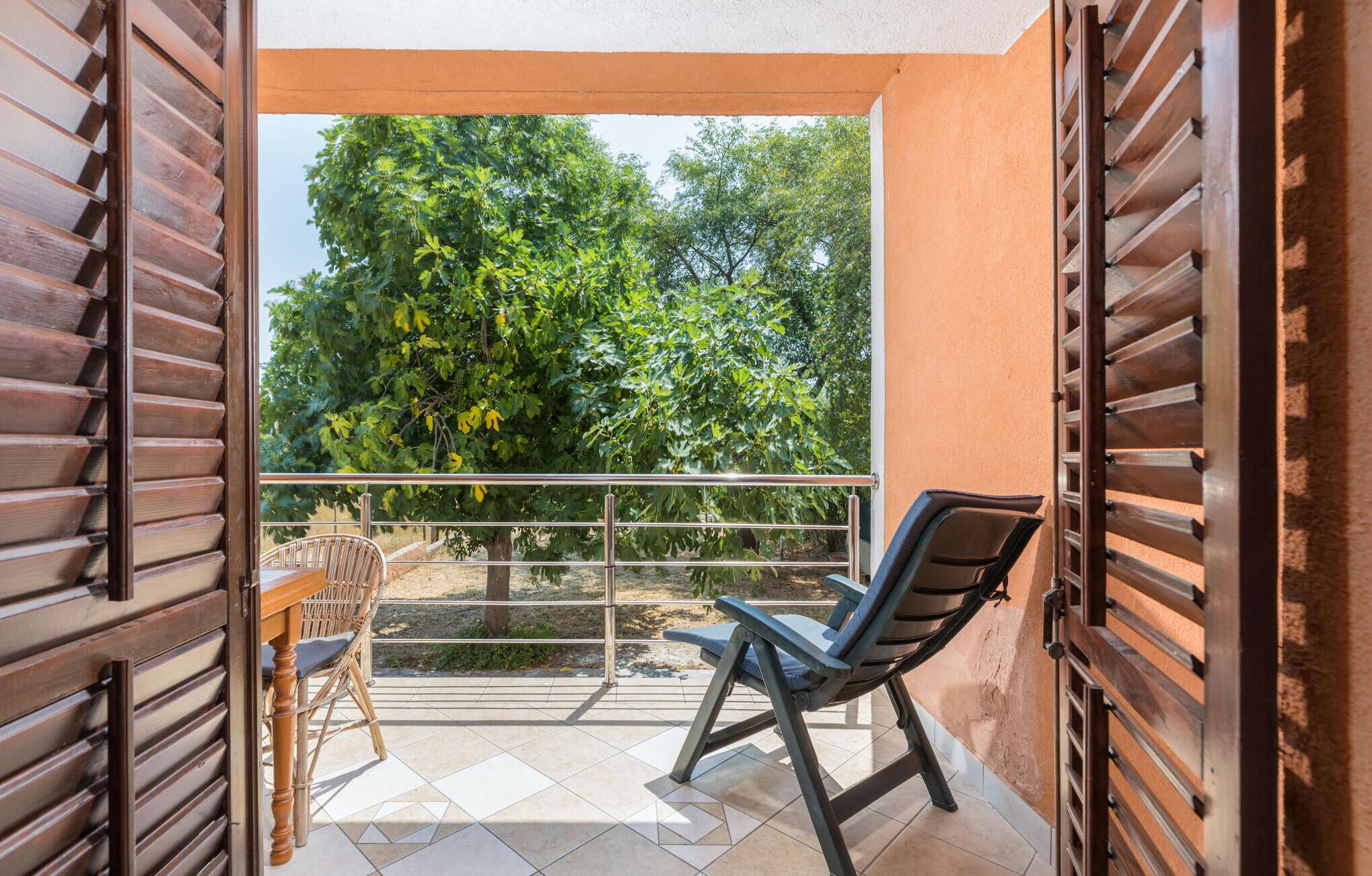 A balcony with a view of a tree and a chair.