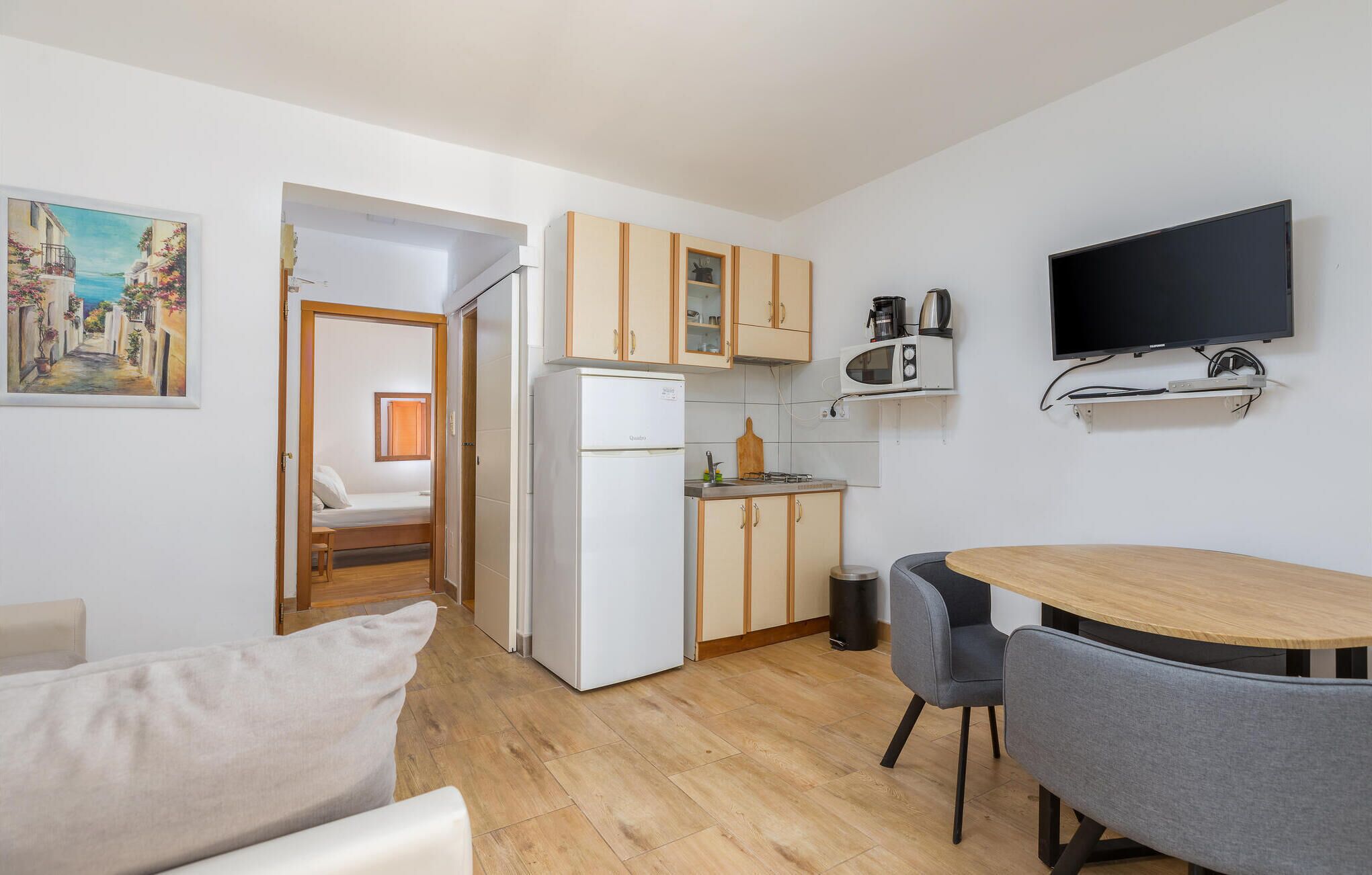A compact living space with a kitchenette, a dining area, and a bedroom.
