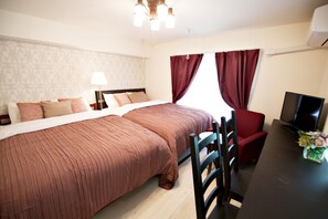 A hotel room with a large bed, a desk with a chair, a TV, and a window with curtains.