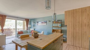 A modern kitchen with a wooden island, a dining table, and a built-in bookshelf.