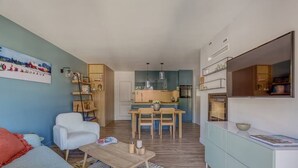A compact living space with a dining area, kitchenette, and a sofa with cushions.