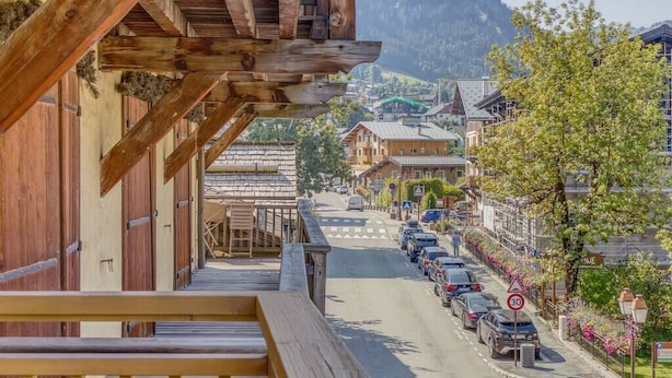 A wooden balcony with a view of a street and buildings in the background.