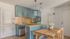 A compact kitchen with a central island, a dining table, and pendant lights.