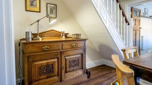 Un comò di legno con cassetti e una lampada, una sedia di legno e una scala con ringhiere bianche.