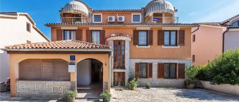 A two-story building with a central courtyard, featuring a covered entrance, stone flooring, and a small garden area.