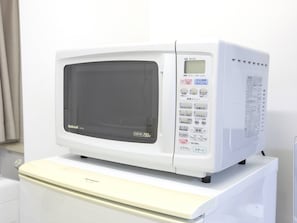 A white microwave oven with a digital display and control panel, placed on a white countertop.