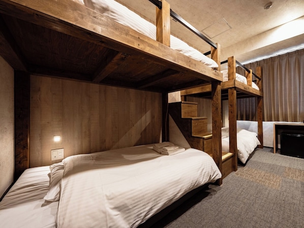 Une chambre avec un lit superposé, des poutres en bois, un bureau et une chaise.