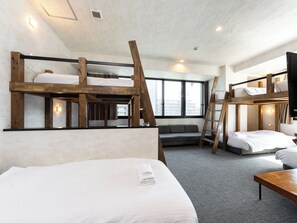 Een kamer met stapelbedden, een slaapbank en een bureau.