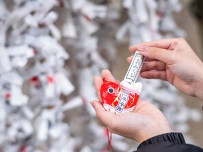 A person holding a red and white object with Japanese text, against a background of white objects.
