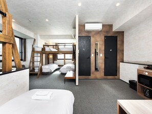 Een moderne hotelkamer met stapelbedden, een bureau, een televisietoestel en een airconditioning.
