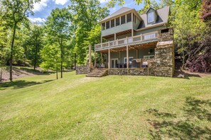 A two-story house with a stone foundation and a balcony. - Secluded Lake Home (Dadeville)
