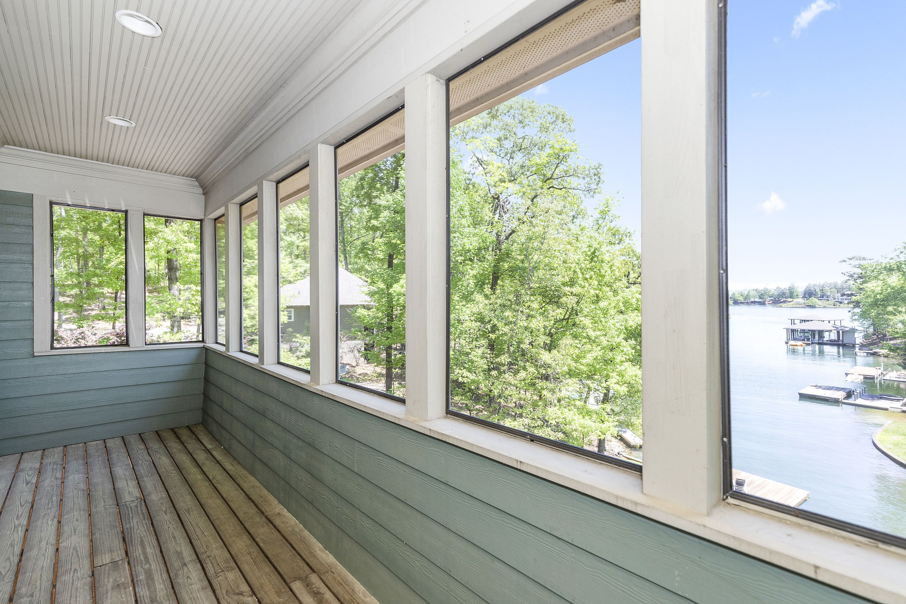 A room with large windows overlooking a lake and dock area.