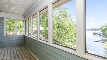 A room with large windows overlooking a lake and dock area.
