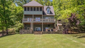 A two-story house with a balcony, stone foundation, and a grassy yard. - Secluded Lake Home (Dadeville)