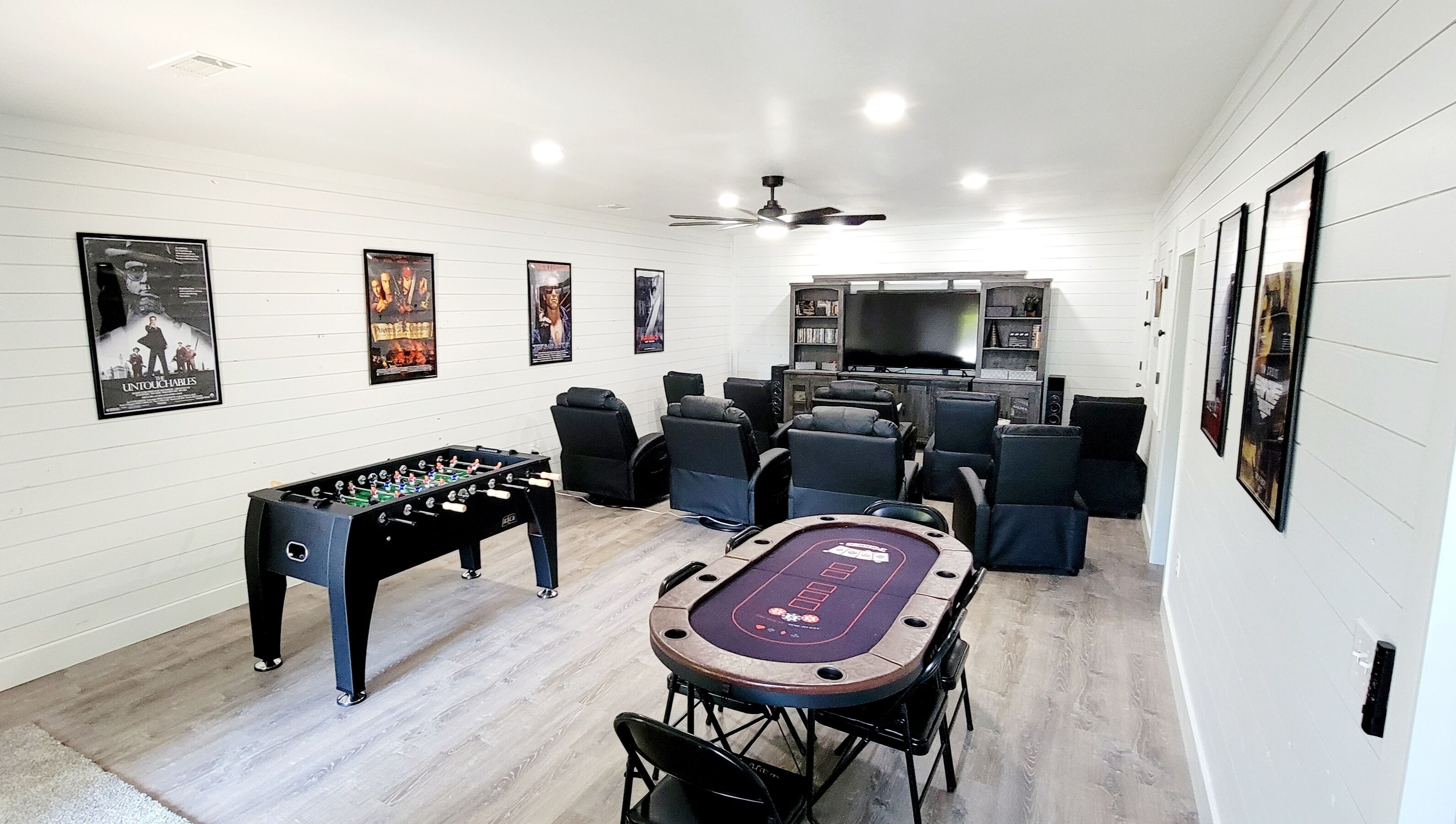 Une pièce équipée d’un baby-foot, d’une table de billard, d’un téléviseur et de plusieurs affiches encadrées accrochées aux murs.