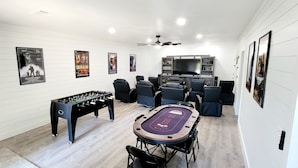 A room with a foosball table, a pool table, a television, and several framed posters on the walls. - Secluded Lake Home (Dadeville)
