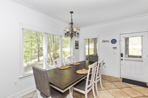 A dining room with a dark wooden table, white chairs, and a chandelier. - Secluded Lake Home (Dadeville)