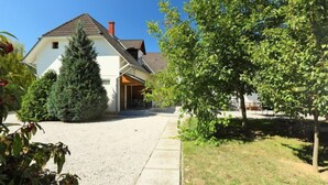 Een woonhuis met een oprit die naar de woning leidt, omringd door groen en bomen.
