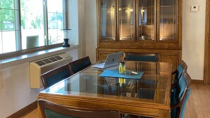 Ein Essbereich mit einem Tisch mit Glasplatte, Holzkästen und einer eingebauten Kabine mit Glastüren.