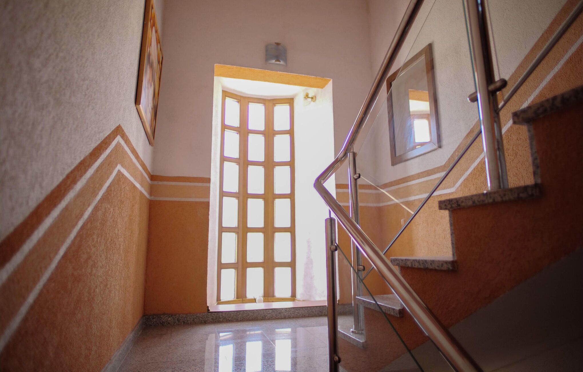 A staircase with a handrail, a door with a grid pattern, and a wall with a decorative molding.