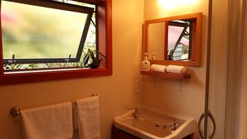 Un baño con ventana, lavamanos, espejo y un perchero para toallas.