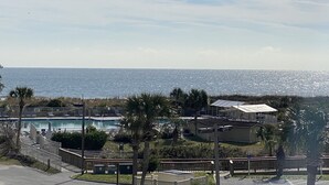 A coastal hotel with a swimming pool, palm trees, and a view of the ocean. - Beautiful Ocean View/ Steps to Beach and Pool (Hilton Head Island)