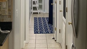 A hallway with a white door, a blue curtain, a Samsung refrigerator, and a tiled floor. - Beautiful Ocean View/ Steps to Beach and Pool (Hilton Head Island)