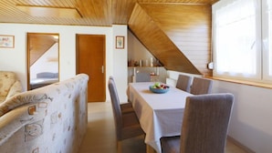 A dining area with a table set for four, a wooden ceiling, and a window with a view. - Familia 2 by Interhome (Balatonszemes)