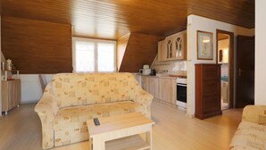 A cozy room with a sofa, a small table, a kitchen area, and a dining table. - Familia 2 by Interhome (Balatonszemes)