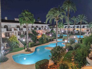 Un complexe hôtelier doté de plusieurs piscines, de palmiers et d’un bâtiment avec des balcons.