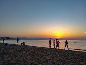 A beach scene with people and a sunset.
